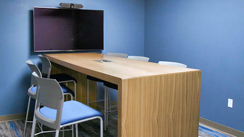 Raised table and chairs in front of a wall mounted screen.