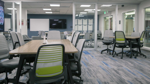 Classroom with conference style tables and chairs.