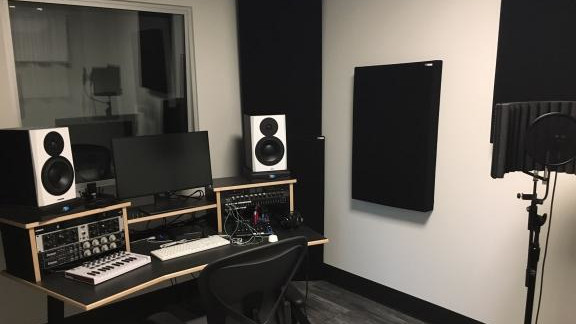 Recording studio with speakers, a computer, and sound baffle panels.