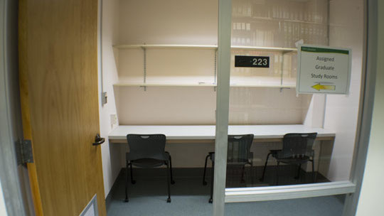 View into study room showing table, shelves, and three chairs