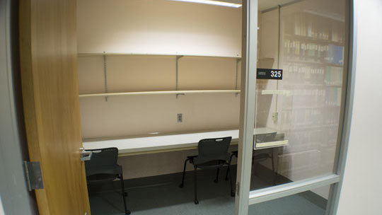 View into study room showing table, shelves, and two chairs