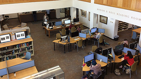 Overhead view of students working at computers with bookshelves on the other side of the room.