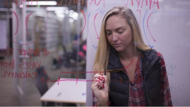 Student writing notes on glass wall