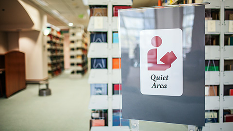 A large quiet area sign with bookstacks in the background.