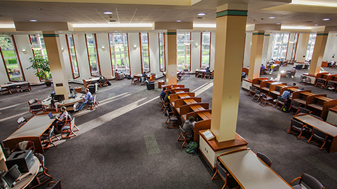 Overhead shot of students working in a large open area with a mix of tables and individual stations.