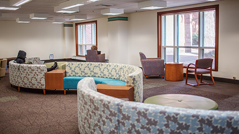 A student sitting at a large curved couch.