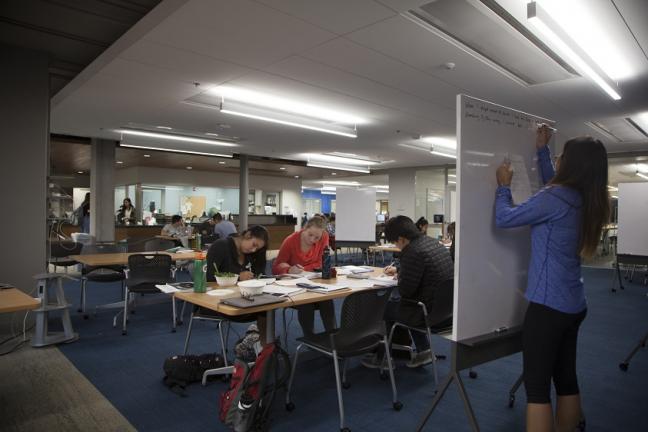 Students working at tables and writing notes on whiteboards