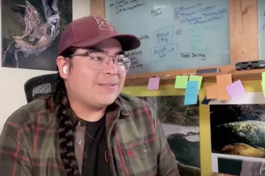 Paul Wolf Wilson, photographer and member of the Klamath and Modoc tribes, sitting in an office.