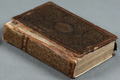 Qur’an published in 1655 features a red leather cover with gold floral motifs.