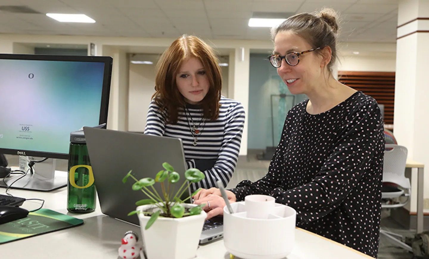 Two people at a desk looking at a computer screen