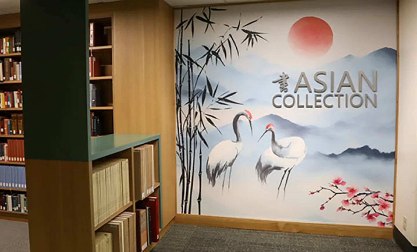 The new mural in the Asian Collections section on the second floor of Knight Library depicts two cranes, a red sun, and bamboo against a backdrop of mountains and sky.