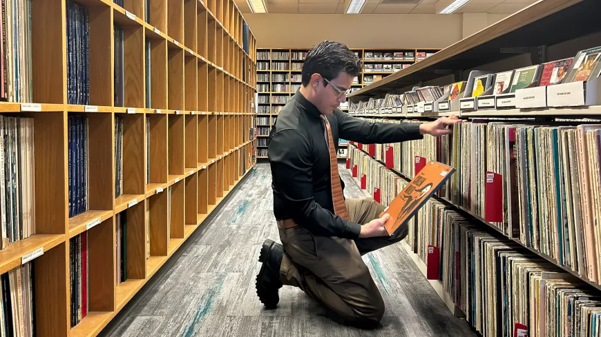 A person kneeling looking at vinyl records