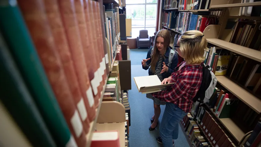 Students looking at books in the stacks