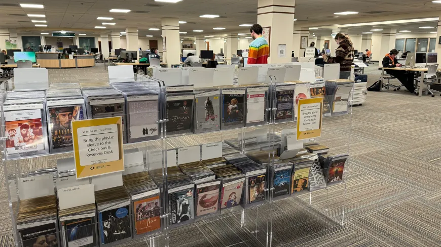 a rack of DVD covers in a large room with computers in the background