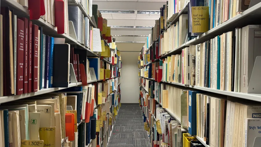 looking down a row of library stacks with shelving on both sides