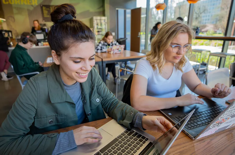 two students working on laptops