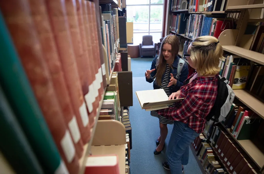 Students looking at books in the stacks