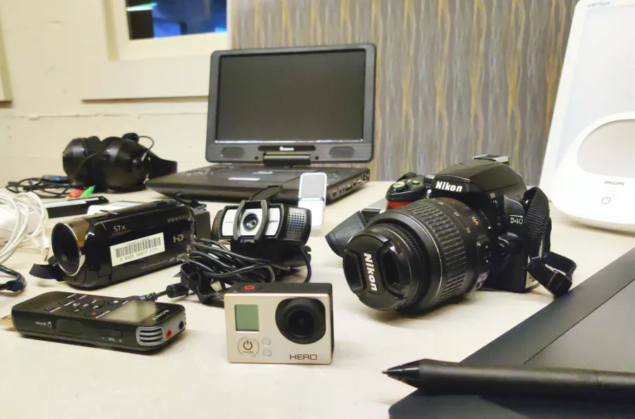 Collection of equipment including cameras, voice recorders, DVD player, pen tablet, and lamp