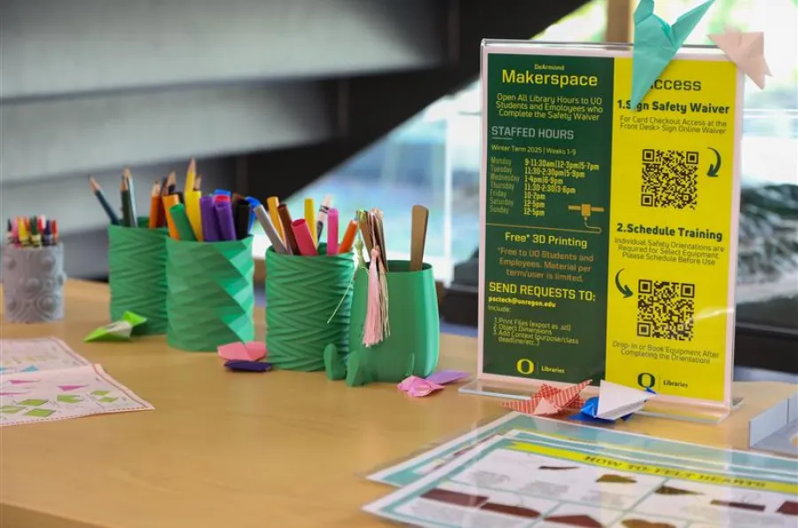 Close up of table with an informational flyer, variety of markers, and origami
